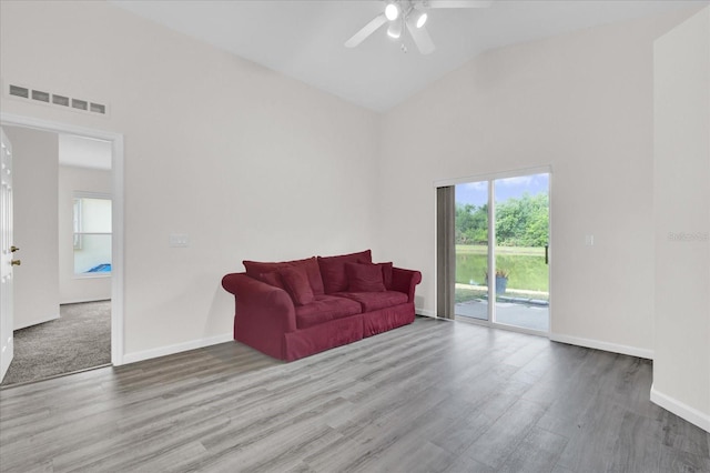 living area with high vaulted ceiling, a ceiling fan, baseboards, wood finished floors, and visible vents