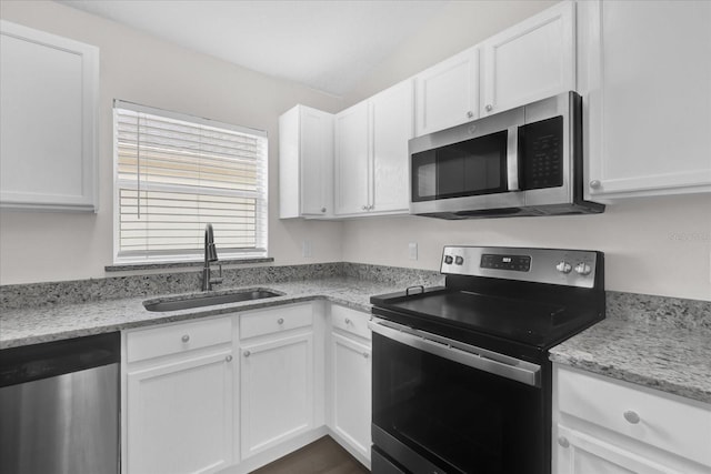 kitchen featuring white cabinets, light stone countertops, appliances with stainless steel finishes, and a sink