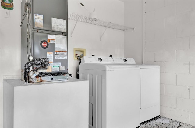 laundry area with concrete block wall, separate washer and dryer, heating unit, and laundry area