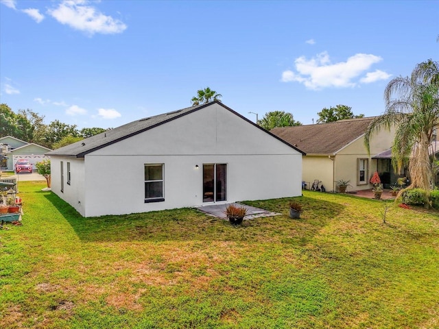 back of property with a yard, a patio area, and stucco siding