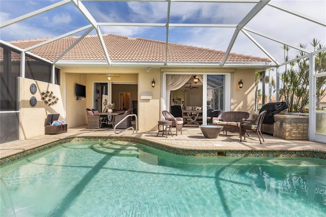 outdoor pool with a patio, ceiling fan, glass enclosure, and area for grilling