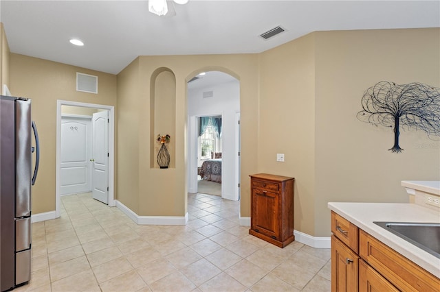clothes washing area featuring arched walkways, baseboards, light tile patterned flooring, and visible vents