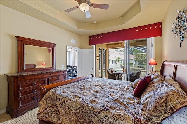 bedroom featuring access to outside, ceiling fan, a tray ceiling, and light colored carpet