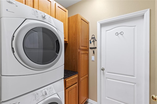 laundry room with stacked washer and dryer and cabinet space