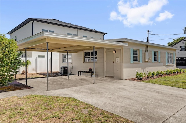rear view of property with central AC unit, fence, and a carport