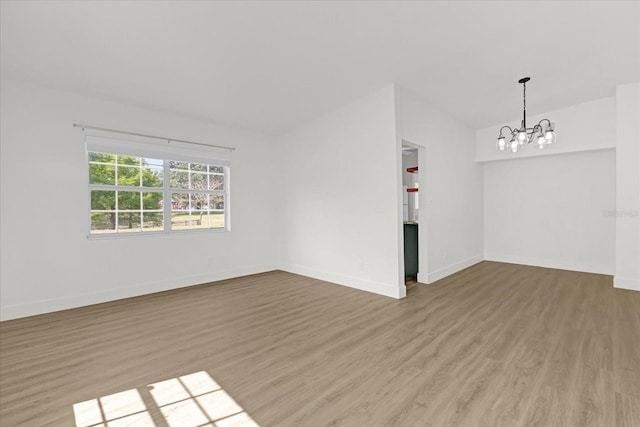 unfurnished room with baseboards, wood finished floors, and a notable chandelier