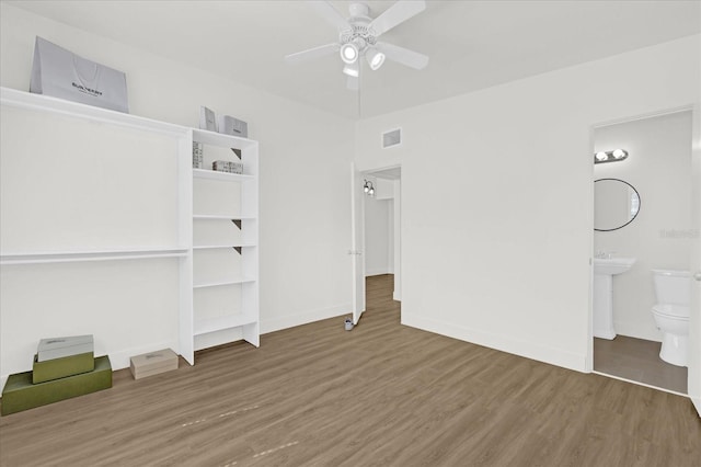 unfurnished bedroom with a ceiling fan, visible vents, wood finished floors, baseboards, and ensuite bath