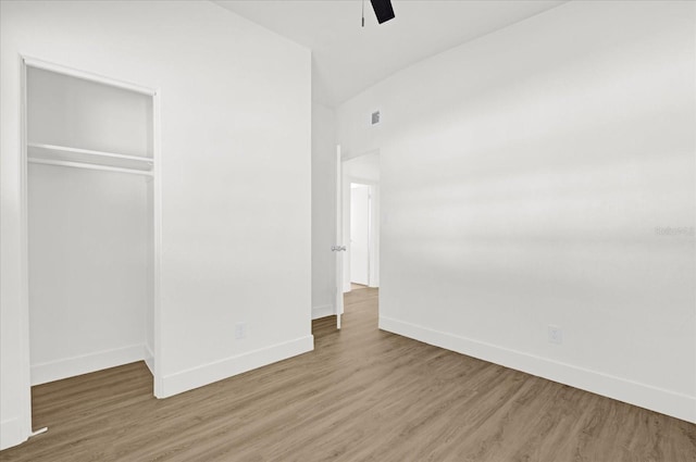 unfurnished bedroom featuring baseboards, wood finished floors, and a closet