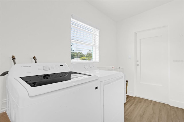 washroom featuring laundry area, washing machine and dryer, baseboards, and light wood finished floors