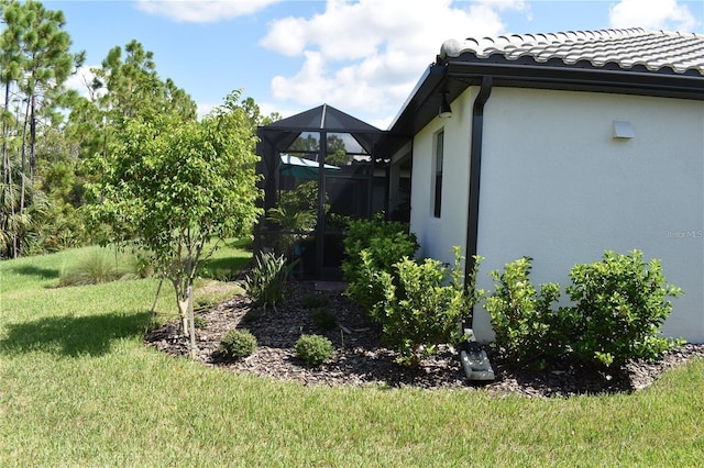 2735 Lavandula Ct, North Port, FL 34289 - view of side of home with a lawn, a tiled roof, a lanai, and stucco siding