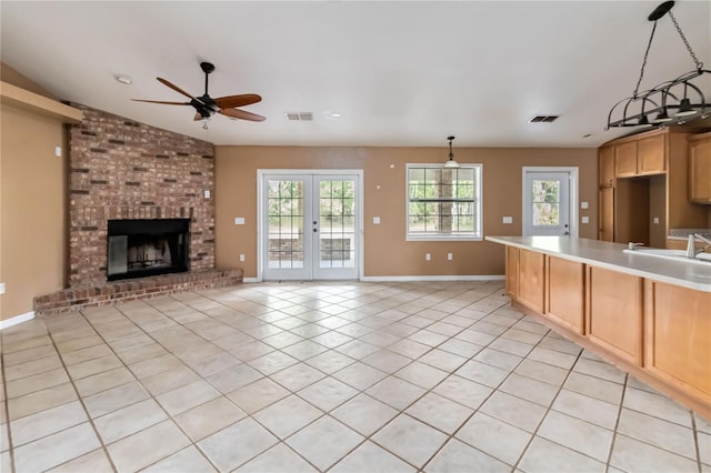 kitchen featuring a sink, light countertops, a brick fireplace, a ceiling fan, and visible vents