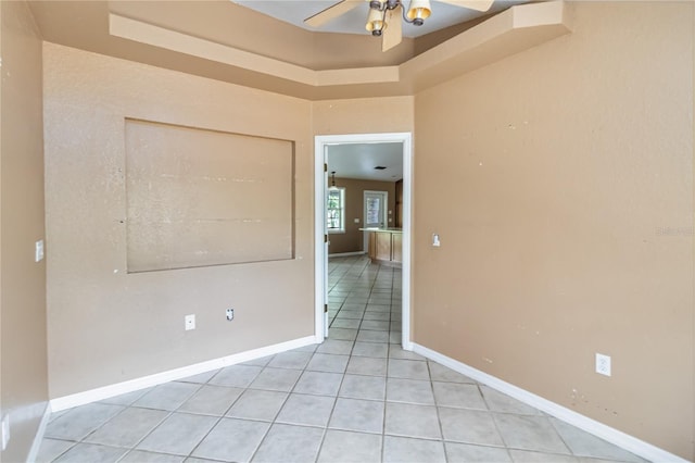 empty room featuring baseboards, a ceiling fan, and light tile patterned floors