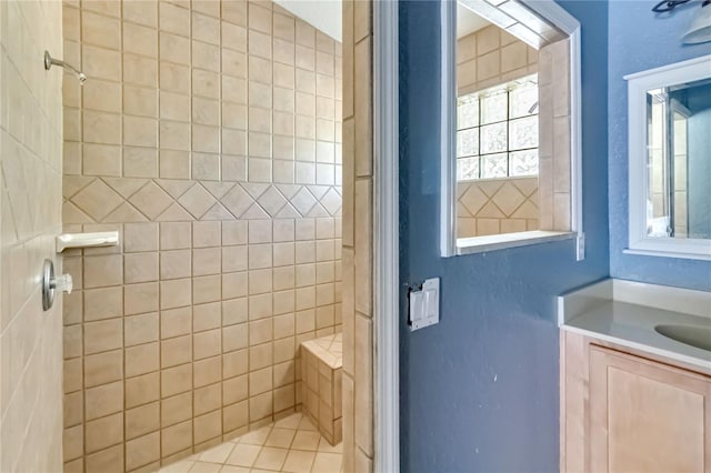 bathroom with vanity, a healthy amount of sunlight, and tiled shower