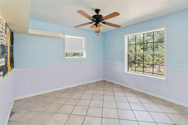 unfurnished room featuring baseboards, ceiling fan, and a wealth of natural light
