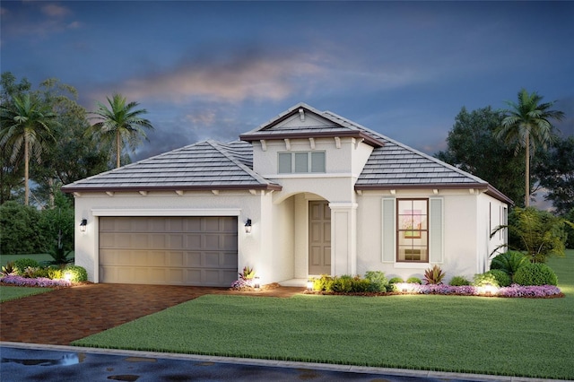 mediterranean / spanish house featuring a garage, stucco siding, a yard, and driveway