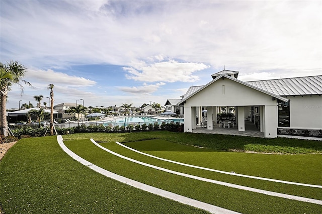 view of property's community featuring a lawn, a patio, and a swimming pool