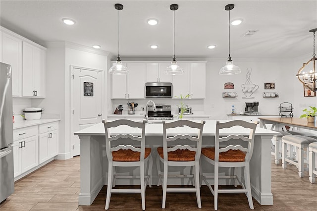 1940 Bell Creek Loop, Fruitland Park, FL 34731 - kitchen featuring stainless steel appliances, light countertops, a kitchen island with sink, light wood-style floors, and ornamental molding