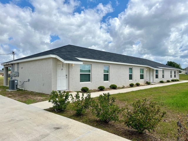 ranch-style home featuring central AC unit, a front lawn, and stucco siding