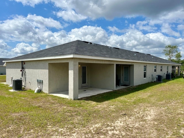 rear view of house with central air condition unit, a patio, a yard, and stucco siding