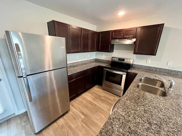 kitchen featuring dark brown cabinetry, a sink, a textured ceiling, stainless steel appliances, and under cabinet range hood