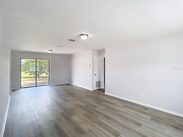 spare room with baseboards, visible vents, and wood finished floors