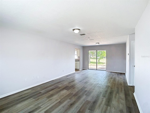 spare room featuring baseboards, visible vents, and wood finished floors