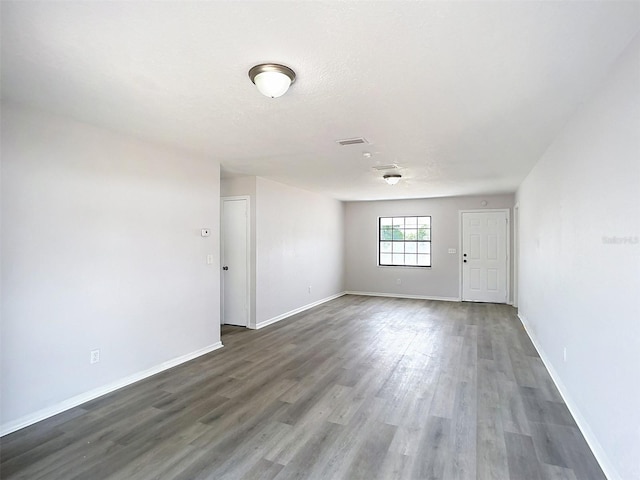 empty room with visible vents, wood finished floors, and baseboards