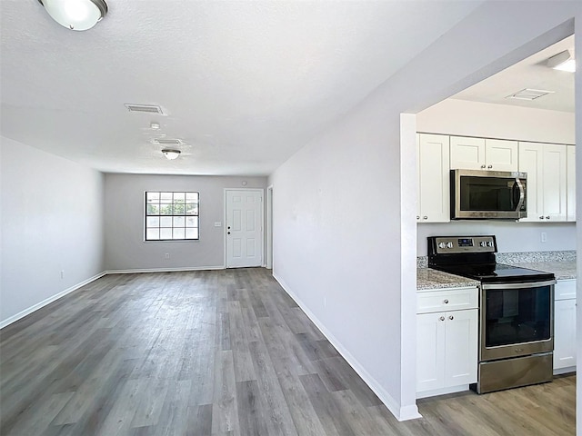 kitchen featuring light wood-type flooring, visible vents, white cabinetry, open floor plan, and appliances with stainless steel finishes