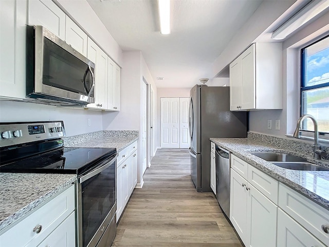 kitchen with white cabinets, light wood-style floors, appliances with stainless steel finishes, and a sink