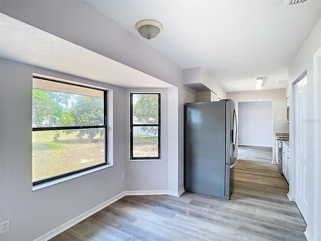 kitchen featuring freestanding refrigerator, baseboards, light countertops, and light wood-style floors
