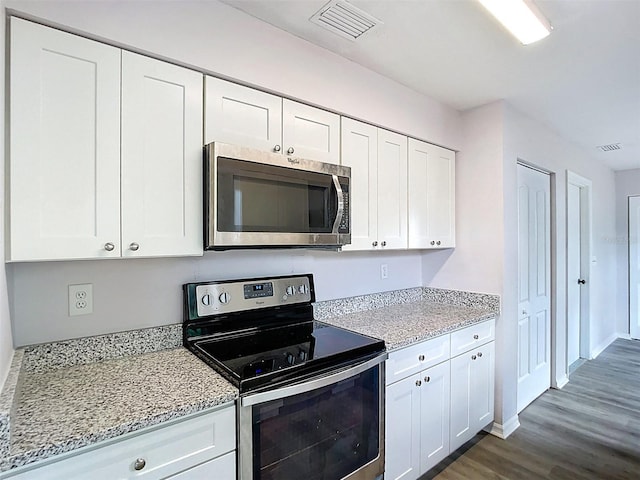 kitchen with dark wood-style flooring, white cabinets, visible vents, and appliances with stainless steel finishes