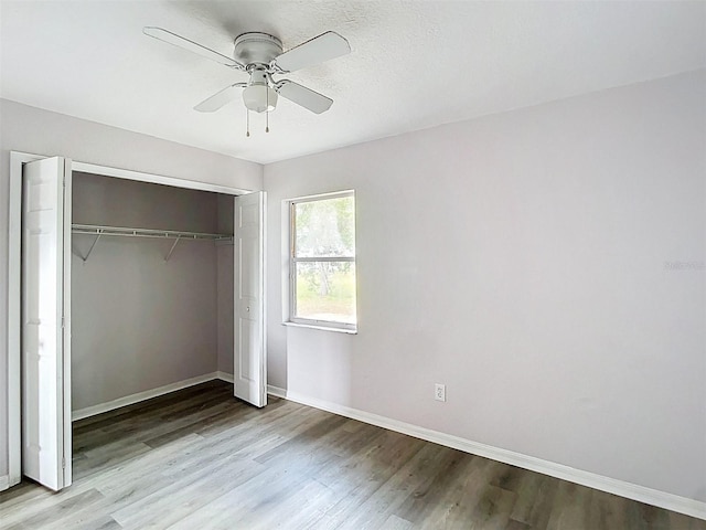 unfurnished bedroom with a closet, baseboards, a ceiling fan, and wood finished floors