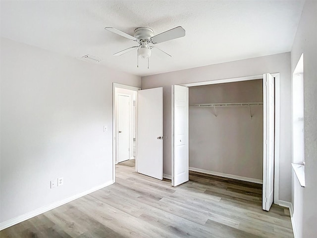 unfurnished bedroom featuring baseboards, a closet, visible vents, and wood finished floors