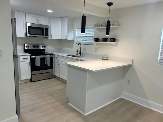 2217 Azalea Ct, Lakeland, FL 33815 - kitchen with stainless steel appliances, a sink, light wood-style flooring, a peninsula, and white cabinets