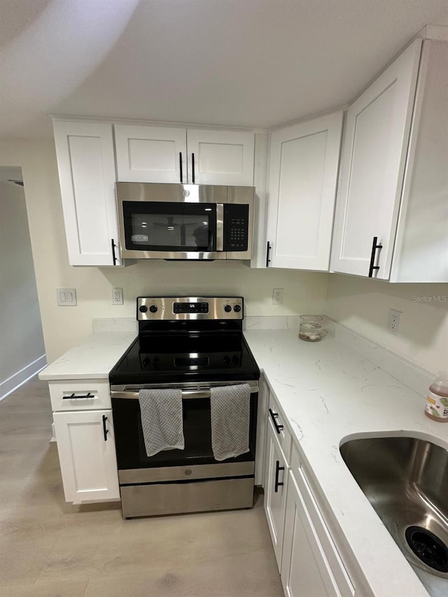 2217 Azalea Ct, Lakeland, FL 33815 - kitchen featuring appliances with stainless steel finishes, white cabinetry, a sink, and light stone countertops