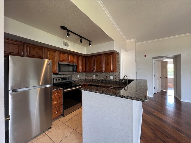 7320 Westpointe Blvd Unit 531, Orlando, FL 32835 - kitchen featuring stainless steel appliances, a peninsula, decorative backsplash, crown molding, and dark stone counters