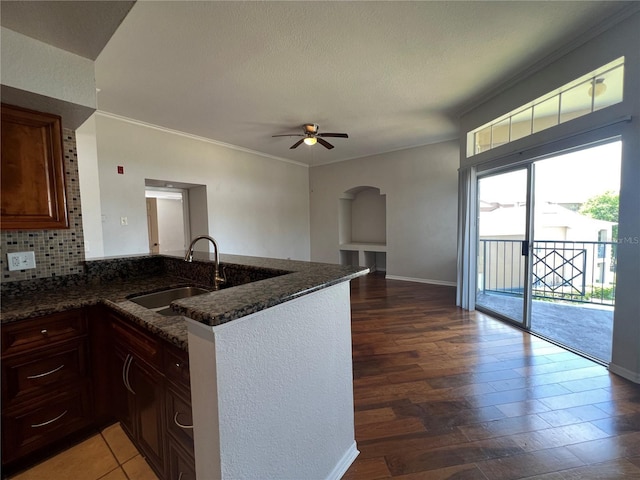 7320 Westpointe Blvd Unit 531, Orlando, FL 32835 - kitchen featuring a sink, ceiling fan, dark stone counters, a peninsula, and wood finished floors