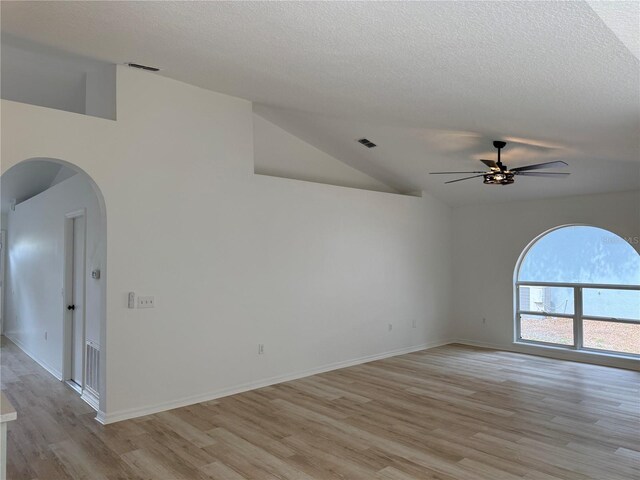 901 Cascades Park Trl, Deland, FL 32720 - empty room featuring ceiling fan, light wood finished floors, a textured ceiling, lofted ceiling, and arched walkways
