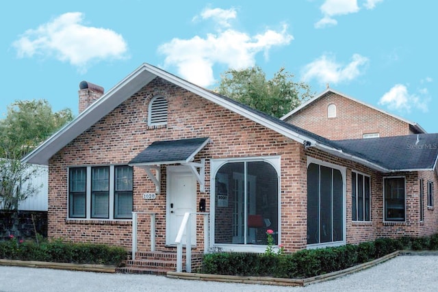 view of front of home featuring brick siding and a chimney