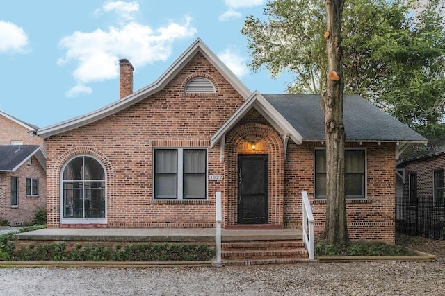 view of front facade with brick siding and a chimney