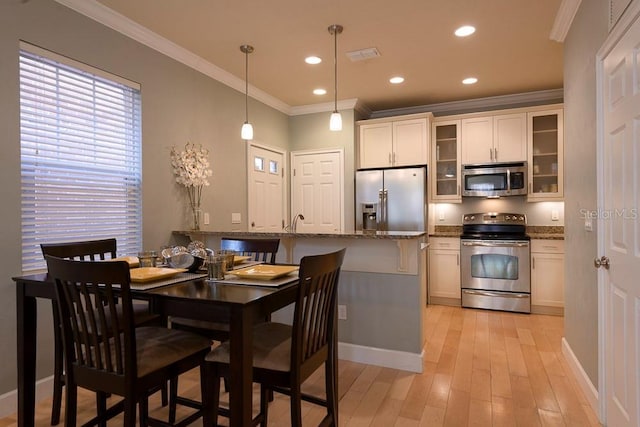 dining room with ornamental molding, light wood-style floors, baseboards, and recessed lighting
