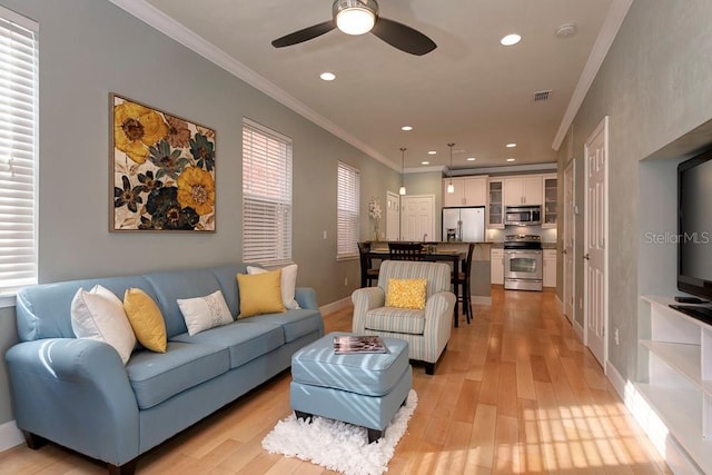 living area featuring light wood-style floors, ceiling fan, recessed lighting, ornamental molding, and baseboards