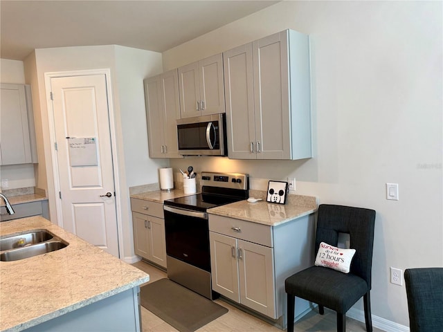 43819 Cattleman Dr, Punta Gorda, FL 33982 - kitchen with stainless steel appliances, a sink, gray cabinets, baseboards, and light stone countertops
