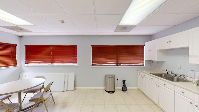 227 Central Ave, Sarasota, FL 34236 - kitchen featuring a sink, white cabinets, light countertops, baseboards, and a drop ceiling