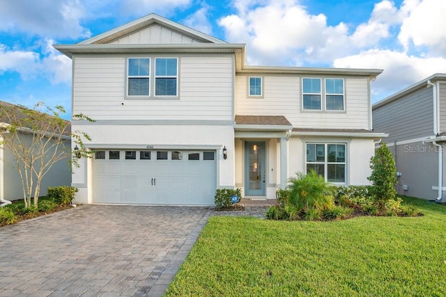 traditional home featuring a garage, decorative driveway, a front yard, and stucco siding