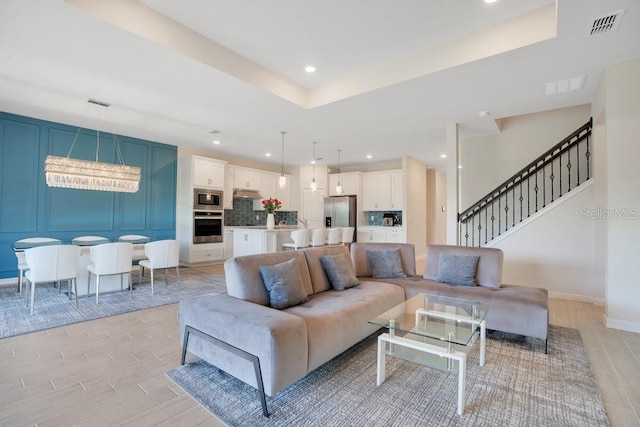 living room featuring wood tiled floors, recessed lighting, stairs, a raised ceiling, and baseboards