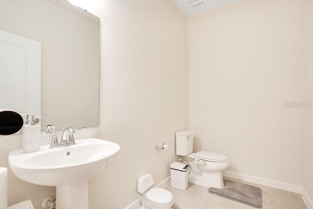 bathroom featuring toilet, baseboards, and a sink