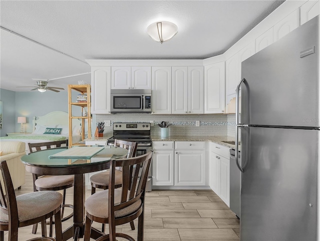 kitchen featuring appliances with stainless steel finishes, a ceiling fan, white cabinets, and tasteful backsplash