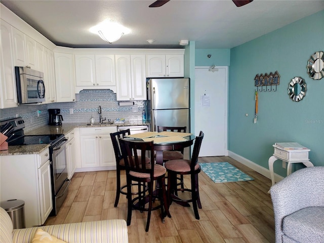 kitchen with stainless steel appliances, light wood finished floors, decorative backsplash, and a sink