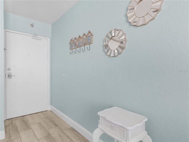 doorway to outside featuring baseboards and light wood-type flooring